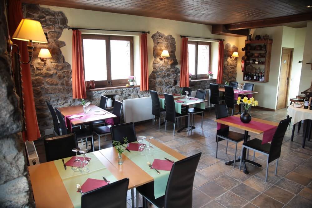 Sala del restaurant amb parets de pedra i cortines vermelles
